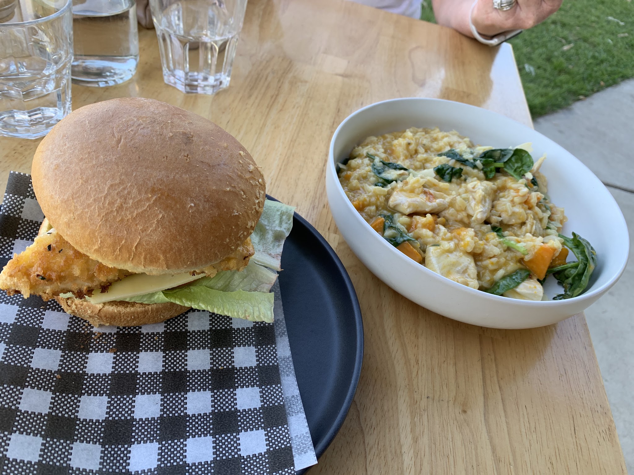 Chicken schnitzel burger and chicken and pumpkin risotto on an outdoor table