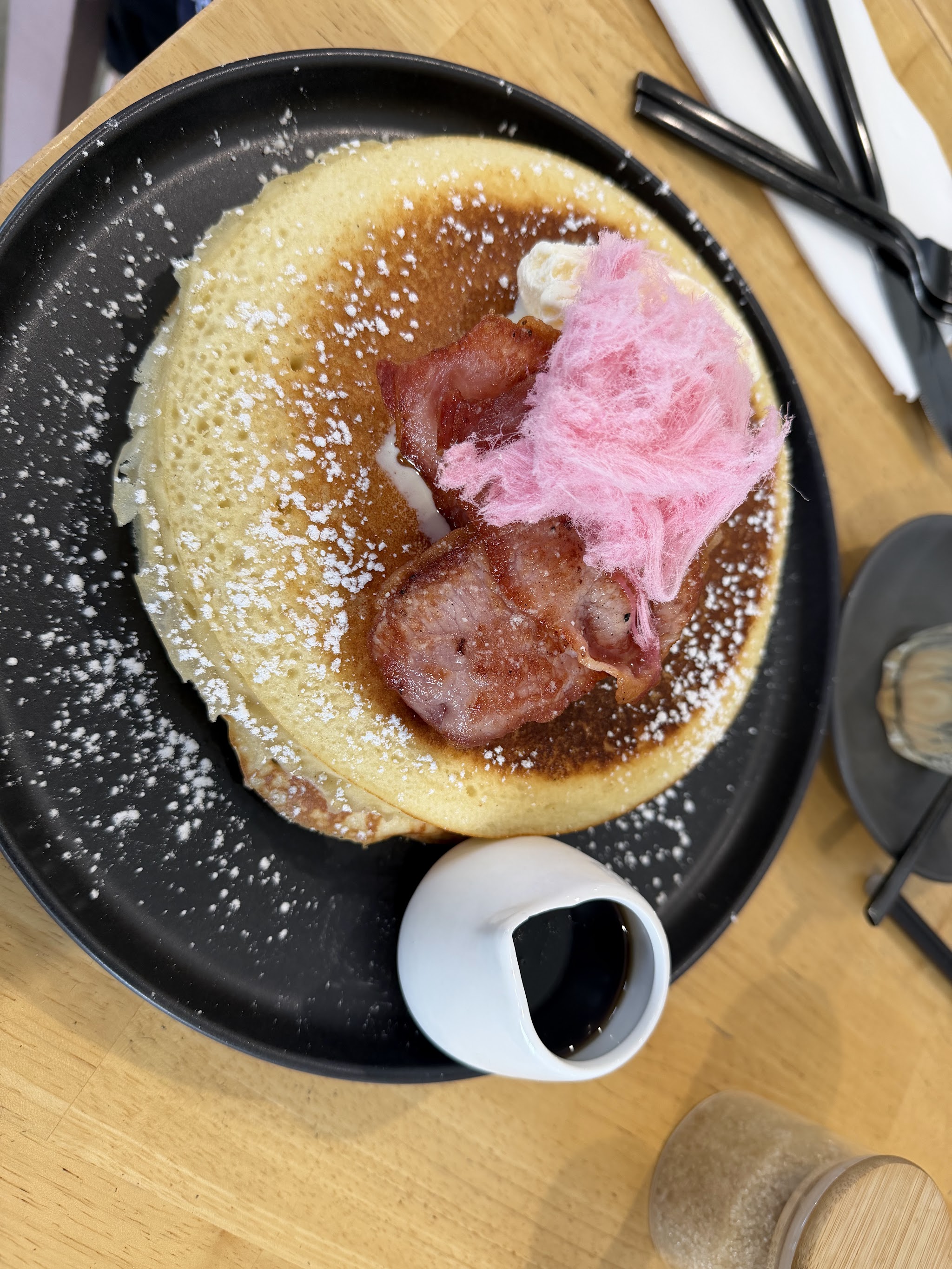 Pancake stack with bacon, fairy floss and a jug of maple syrup